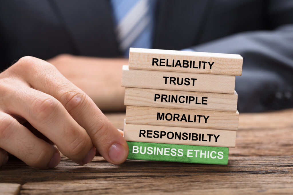 Businessman Holding Red Business Ethics Block Under Wooden Tower